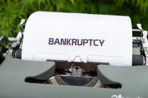 Close-up of a typewriter with a sheet of paper displaying the word 'BANKRUPTCY,' representing financial distress or legal bankruptcy proceedings.