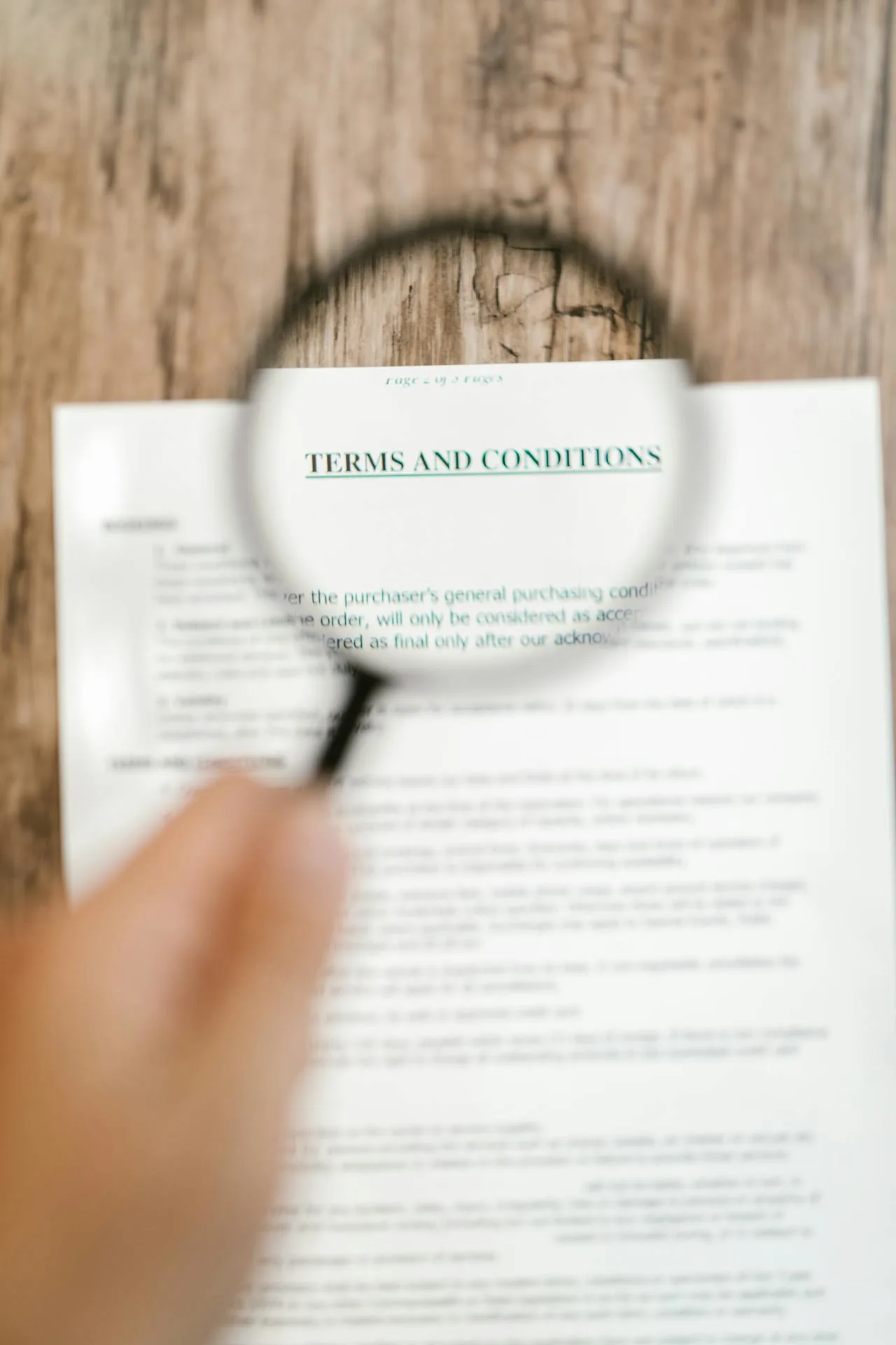 Hand holding a magnifying glass over a document, symbolizing close examination of bankruptcy terms and legal conditions.