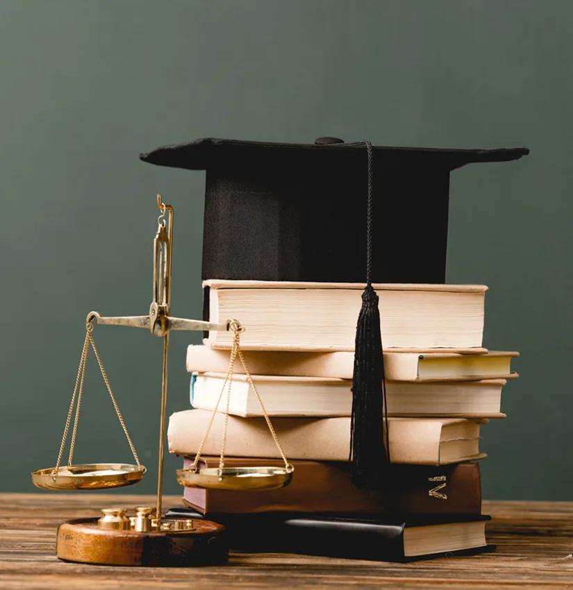 Scales of justice beside a stack of law books topped with a graduation cap, representing legal education and due diligence in real estate law.