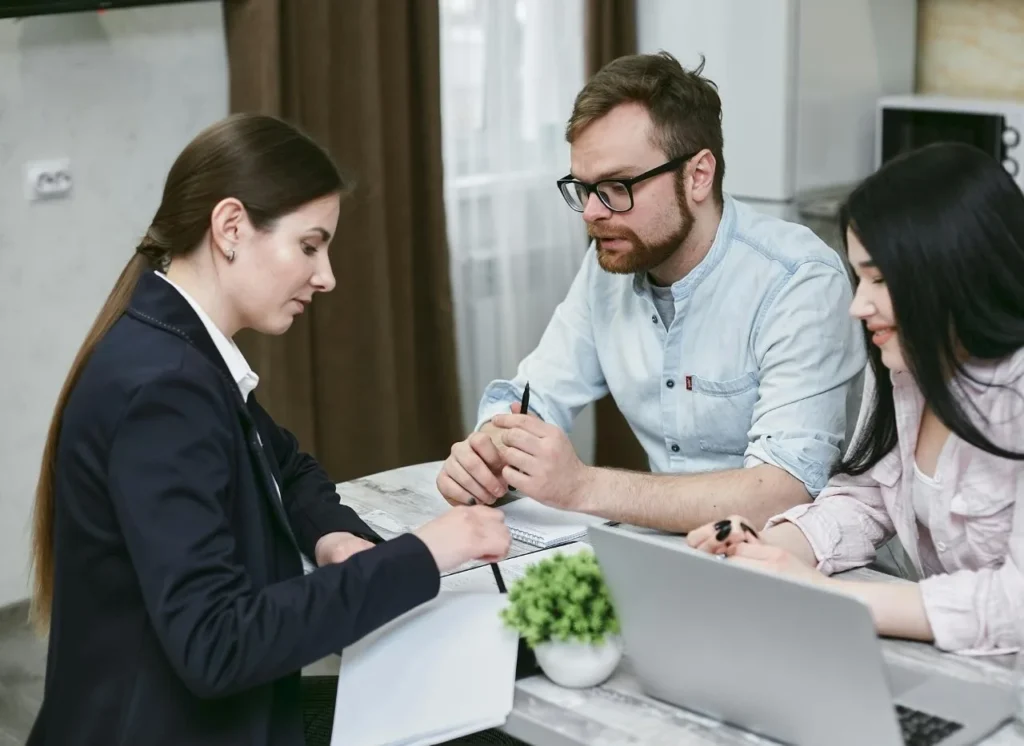Legal advisor discussing documents with a couple at a desk, representing consultation on UAE defense procurement contracts.