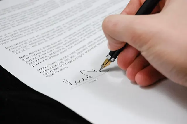 A person signing on the document with an ink pen 