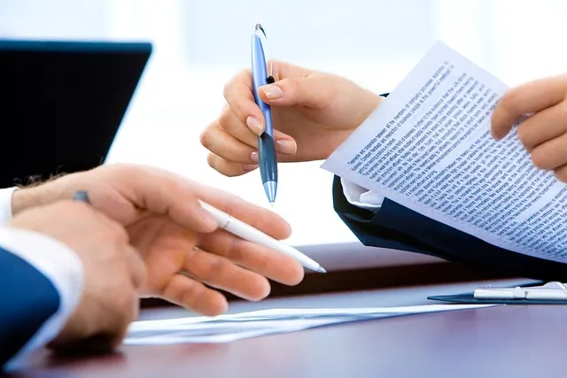 Two people discussing the agreement with pens and agreement in their hands