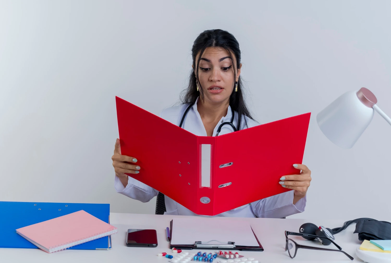 A woman checking the documents in a red file with a stethoscope around her neck
